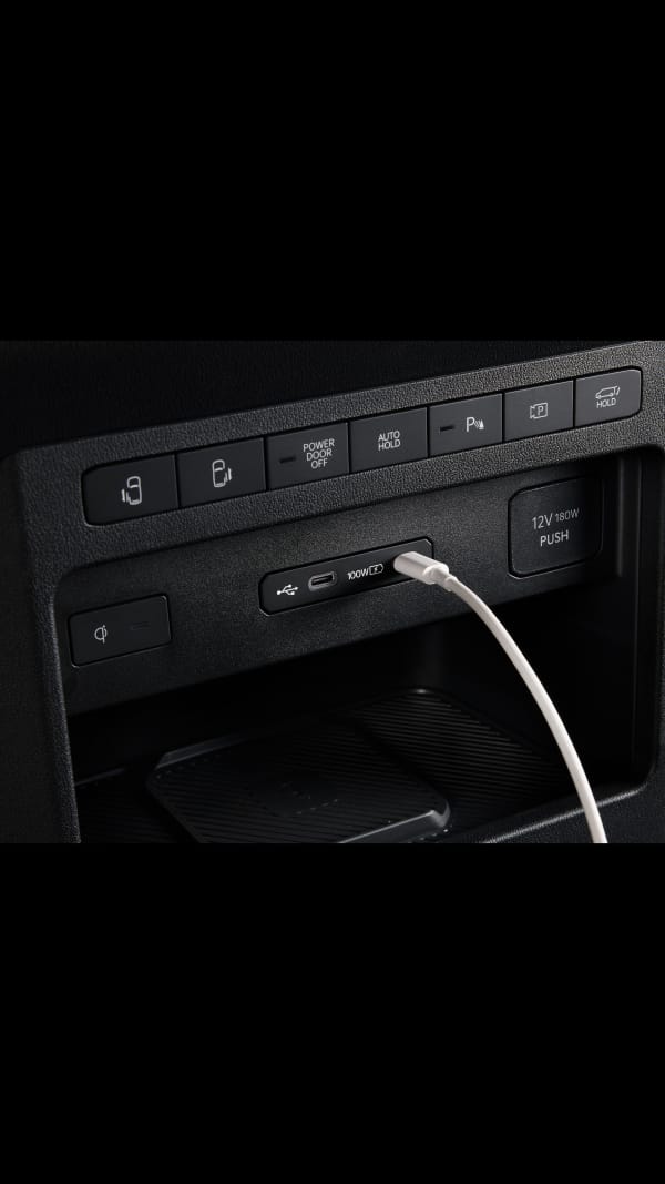 Nahaufnahme eines 100-W-USB-C-Anschlusses im Kia PV5 WAV beim Laden eines Geräts im vorderen Innenraum.
